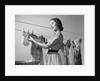 1950s Smiling Woman Housewife Hanging Wash Child Dress On Clothesline To Dry by Anonymous