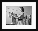 1950s Smiling Woman Housewife Hanging Wash Child Dress On Clothesline To Dry by Anonymous