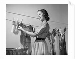 1950s Smiling Woman Housewife Hanging Wash Child Dress On Clothesline To Dry by Anonymous