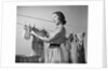1950s Smiling Woman Housewife Hanging Wash Child Dress On Clothesline To Dry by Anonymous
