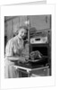 1950s Smiling Woman Housewife Wearing Apron Taking Large Roast Beef From Electric Oven In Kitchen Looking At Camera by Anonymous