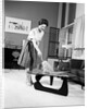 1950s 1960s Woman Wearing A White Blouse & Plaid Skirt Dusting With A Feather Duster A Glass Top Coffee Table by Anonymous