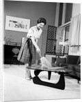 1950s 1960s Woman Wearing A White Blouse & Plaid Skirt Dusting With A Feather Duster A Glass Top Coffee Table by Anonymous