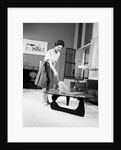 1950s 1960s Woman Wearing A White Blouse & Plaid Skirt Dusting With A Feather Duster A Glass Top Coffee Table by Anonymous
