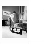 1950s 1960s Woman Wearing A White Blouse & Plaid Skirt Dusting With A Feather Duster A Glass Top Coffee Table by Anonymous