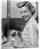 1950s Smiling Blonds Woman Mother Warming A Baby Bottle Of Milk In Kitchen Looking At Camera by Anonymous
