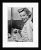 1950s Smiling Blonds Woman Mother Warming A Baby Bottle Of Milk In Kitchen Looking At Camera by Anonymous
