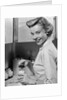 1950s Smiling Blonds Woman Mother Warming A Baby Bottle Of Milk In Kitchen Looking At Camera by Anonymous