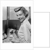 1950s Smiling Blonds Woman Mother Warming A Baby Bottle Of Milk In Kitchen Looking At Camera by Anonymous