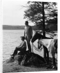 1930s Man Standing On Rock Lakeside Holding Reins Of Two Horses With Woman Seated Beside Looking Off To Side by Anonymous