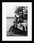 1930s Man Standing On Rock Lakeside Holding Reins Of Two Horses With Woman Seated Beside Looking Off To Side by Anonymous