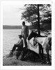 1930s Man Standing On Rock Lakeside Holding Reins Of Two Horses With Woman Seated Beside Looking Off To Side by Anonymous