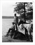 1930s Man Standing On Rock Lakeside Holding Reins Of Two Horses With Woman Seated Beside Looking Off To Side by Anonymous