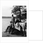 1930s Man Standing On Rock Lakeside Holding Reins Of Two Horses With Woman Seated Beside Looking Off To Side by Anonymous