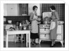 1930s Woman Housewife And Friend Wearing Apron Cooking Food In Kitchen On Gas Stove Indoor by Anonymous