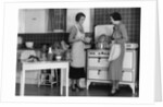 1930s Woman Housewife And Friend Wearing Apron Cooking Food In Kitchen On Gas Stove Indoor by Anonymous