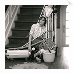 1960s 1970s Exhausted Housewife Sitting At Bottom Of Stairs Surrounded By House Cleaning Equipment by Anonymous