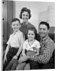 1960s Family Sitting On Couch Smiling Looking At Camera by Anonymous