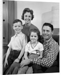 1960s Family Sitting On Couch Smiling Looking At Camera by Anonymous