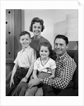 1960s Family Sitting On Couch Smiling Looking At Camera by Anonymous