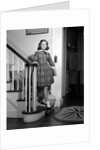 1950s Teenage Girl In Plaid Dress And White Ankle Socks On Stairway Holding Banister Carrying School Books Looking At Camera by Anonymous
