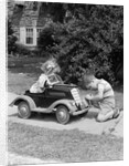 1940s 1930s Boy On Sidewalk Fixing Headlight Of Toy Car Driven By Little Girl Playing Outdoor by Anonymous