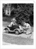 1940s 1930s Boy On Sidewalk Fixing Headlight Of Toy Car Driven By Little Girl Playing Outdoor by Anonymous