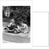 1940s 1930s Boy On Sidewalk Fixing Headlight Of Toy Car Driven By Little Girl Playing Outdoor by Anonymous
