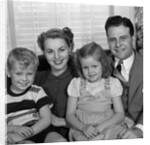 1940s 1950s Portrait Of Smiling Family Man Woman Boy Girl Sitting On Sofa Looking At Camera by Anonymous