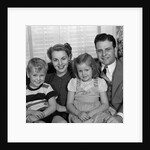 1940s 1950s Portrait Of Smiling Family Man Woman Boy Girl Sitting On Sofa Looking At Camera by Anonymous