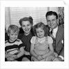 1940s 1950s Portrait Of Smiling Family Man Woman Boy Girl Sitting On Sofa Looking At Camera by Anonymous