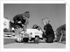 1950s Boy And Girl Playing At Repairing Toy Car by Anonymous