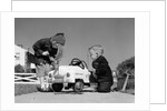1950s Boy And Girl Playing At Repairing Toy Car by Anonymous