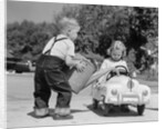 1950s Little Boy Playing Gas Station Pouring Water Into Toy Car For Little Girl by Anonymous