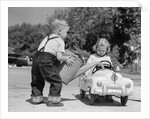 1950s Little Boy Playing Gas Station Pouring Water Into Toy Car For Little Girl by Anonymous