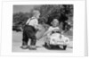 1950s Little Boy Playing Gas Station Pouring Water Into Toy Car For Little Girl by Anonymous