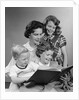 1950s Portrait Mother Two Daughters And Son Reading Book Together by Anonymous