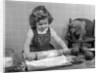 1950s Little Girl Rolling Out Apple Pie Crust On Kitchen Table With Cocker Spaniel Puppy Watching by Anonymous