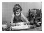 1950s Little Girl Rolling Out Apple Pie Crust On Kitchen Table With Cocker Spaniel Puppy Watching by Anonymous