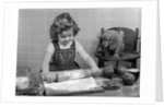 1950s Little Girl Rolling Out Apple Pie Crust On Kitchen Table With Cocker Spaniel Puppy Watching by Anonymous