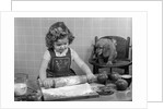 1950s Little Girl Rolling Out Apple Pie Crust On Kitchen Table With Cocker Spaniel Puppy Watching by Anonymous