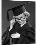 1950s Little Blond Girl Wearing Scholarly Glasses Graduation Cap And Gown Looking At Camera by Anonymous