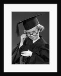 1950s Little Blond Girl Wearing Scholarly Glasses Graduation Cap And Gown Looking At Camera by Anonymous