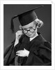 1950s Little Blond Girl Wearing Scholarly Glasses Graduation Cap And Gown Looking At Camera by Anonymous