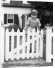 1940s Child Boy Standing Swinging On White Picket Fence Gate Smiling Looking At Camera by Anonymous