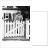 1940s Child Boy Standing Swinging On White Picket Fence Gate Smiling Looking At Camera by Anonymous