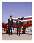 1960s Two Businessmen In Suits And Hats Carrying Briefcases Walking From A Small Twin Prop Business Airplane Talking by Anonymous