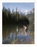 1970s Man Fisherman Red Shirt In Rocky Mountains Stream Lake Fly Rod Catch Splashing On Line Net by Anonymous
