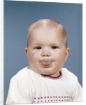 1960s Portrait Of Cute Blond Chubby Baby Looking At Camera Sticking Out Tongue by Anonymous