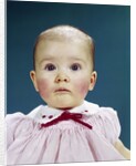 1960s Portrait Baby Girl Silly Facial Expression Red Bow At Collar Looking At Camera by Anonymous